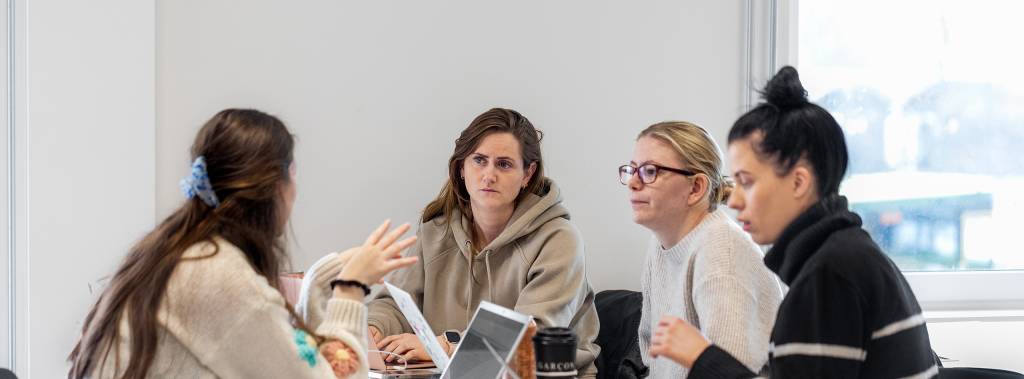En gruppe kvinnelige studenter snakker sammen i et klasserom 