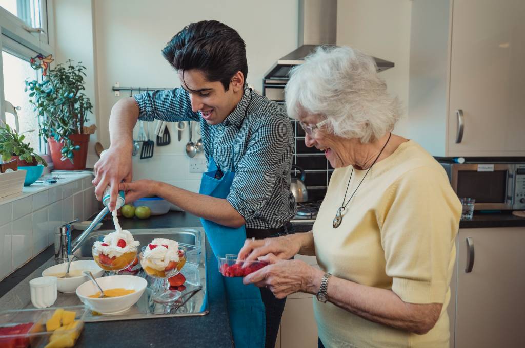 Eldre dame og ung mann står på et kjøkken og lager dessert!''