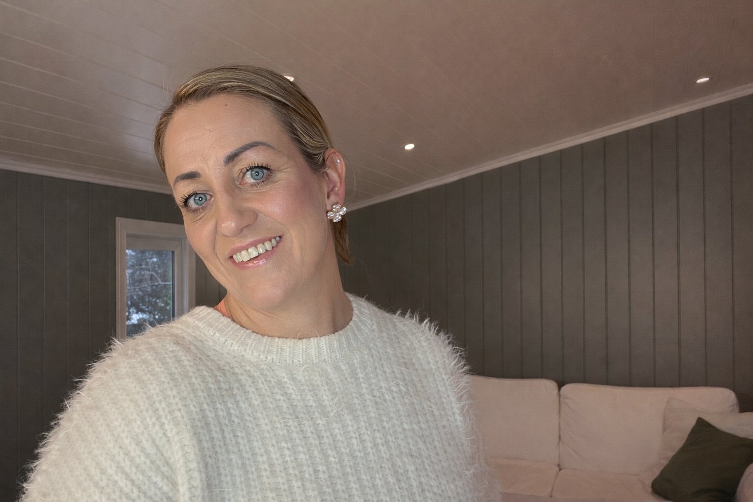 Kvinne ser mot kamera og smiler.