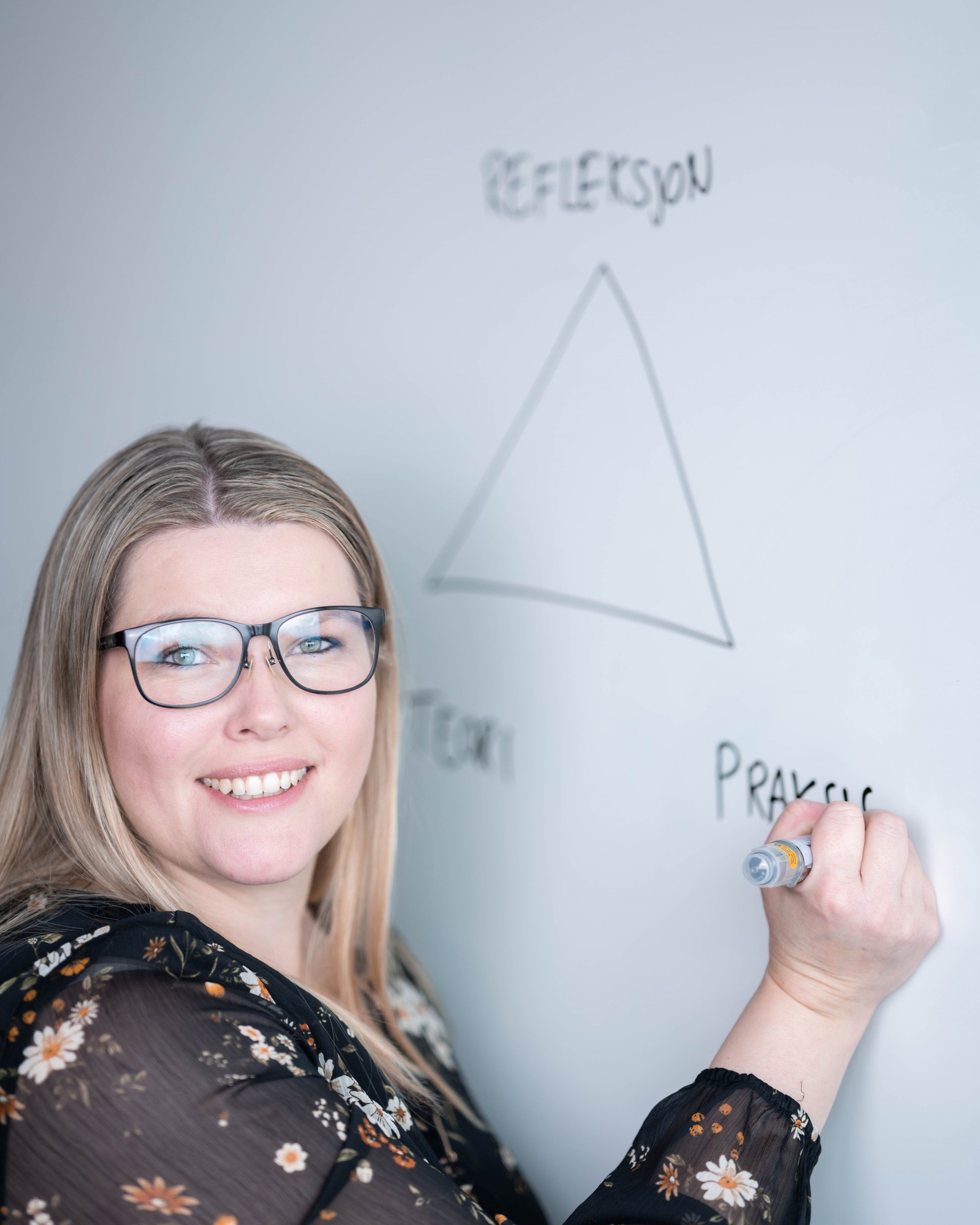 Kvinne med briller som tegner på whiteboard