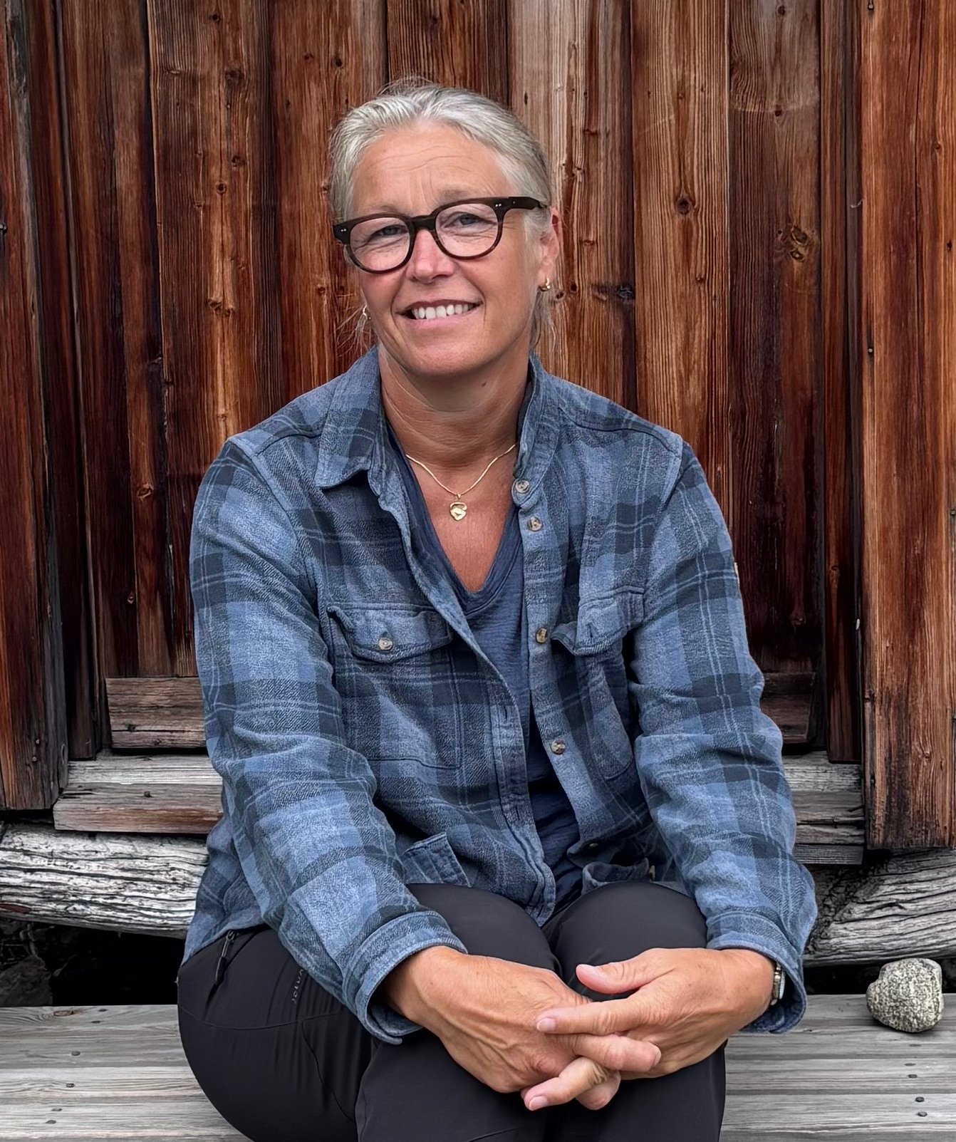 Lena Moland sitter smilende med hendene foldet på en gammel stabburstrapp.
