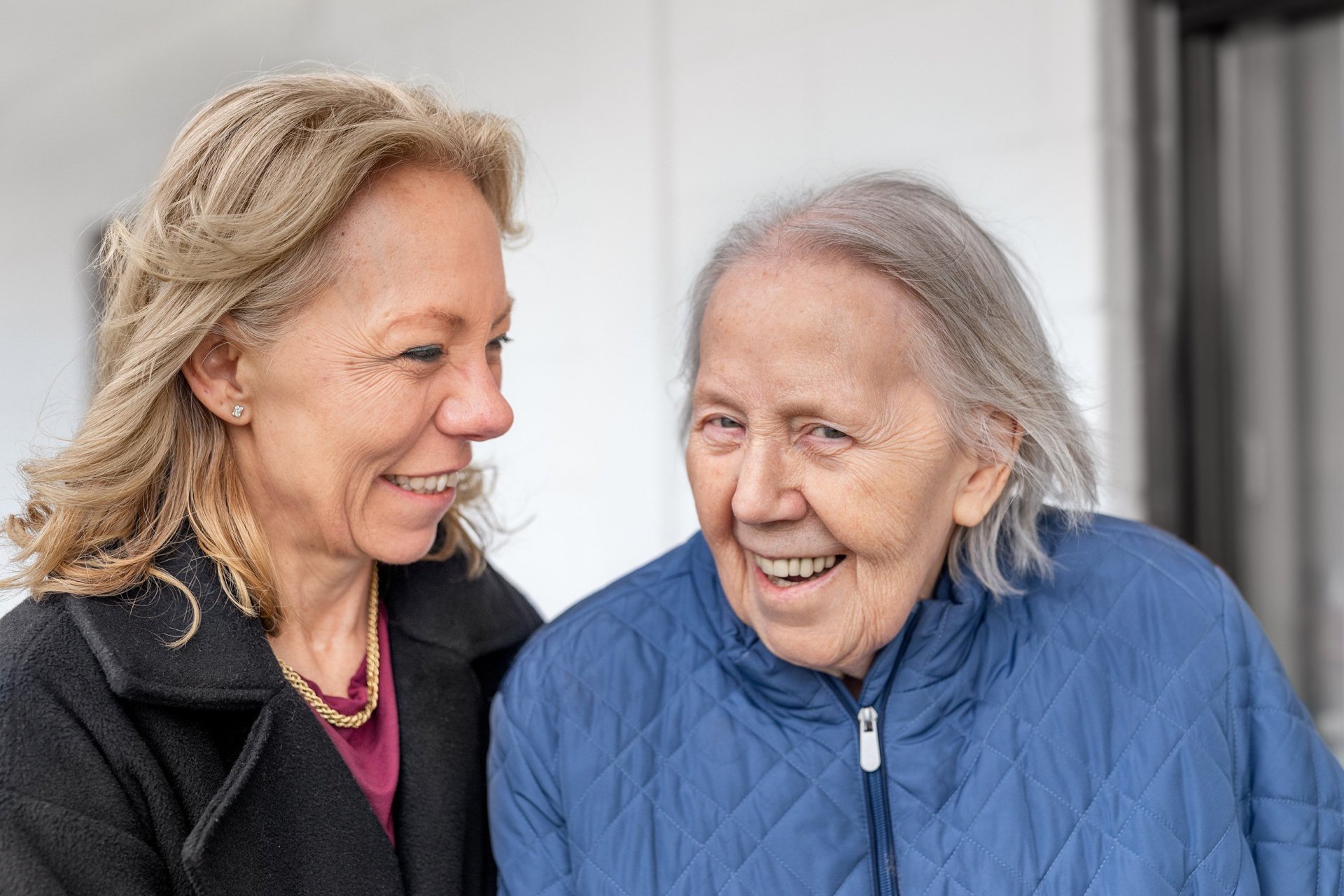 To kvinner, en eldre enn den andre, står samme og smiler