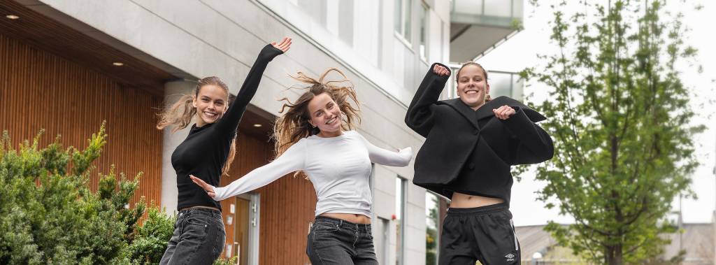 Tre unge kvinner som jubler og hopper i luften 