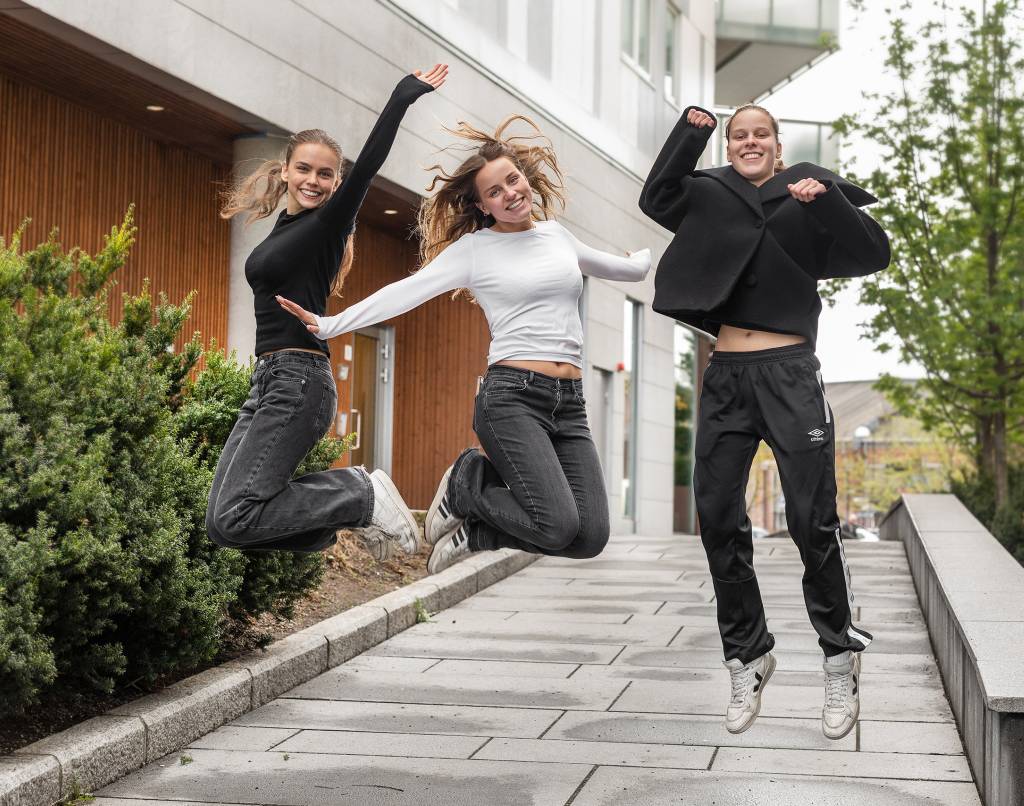 Tre unge kvinner som jubler og hopper i luften 