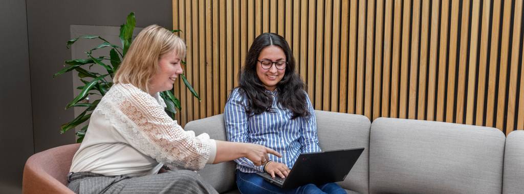 To kvinnelige studenter på Fagskolen Diakonova snakker og ser på en laptop