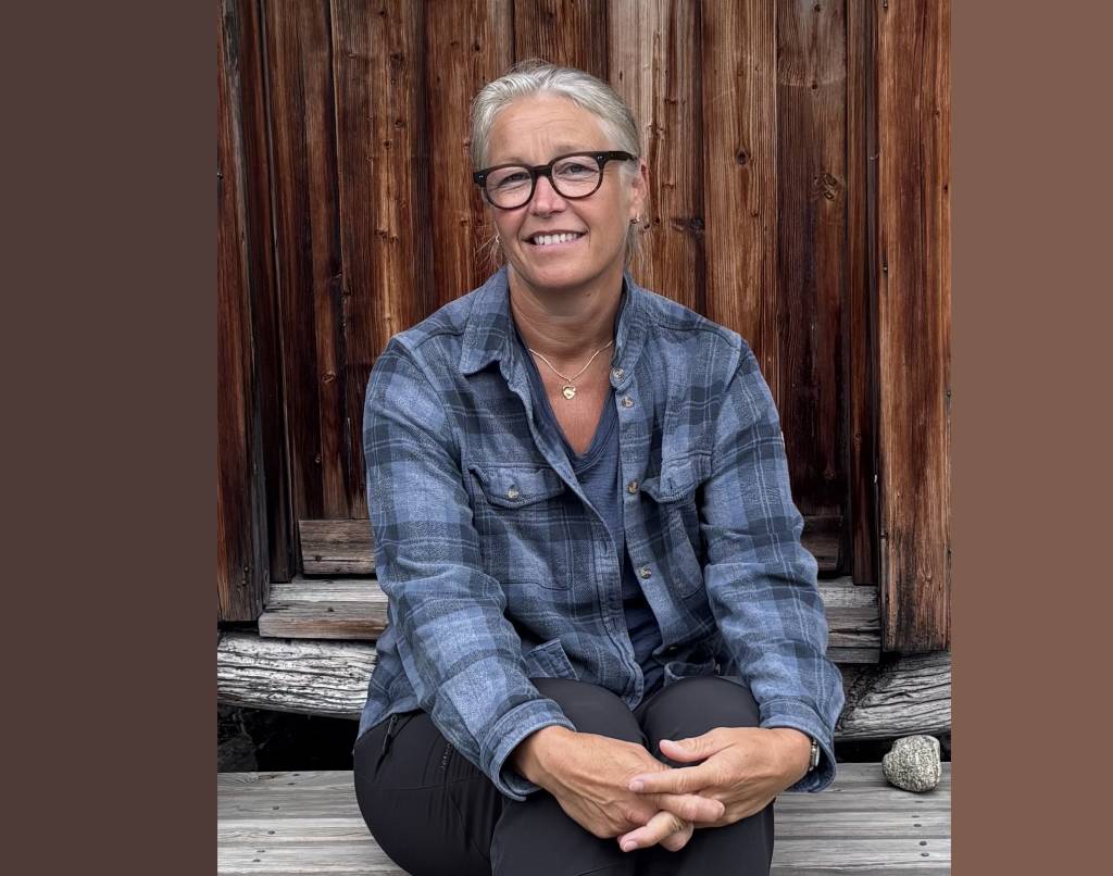 Lena Moland sitter smilende med hendene foldet på en gammel stabburstrapp.