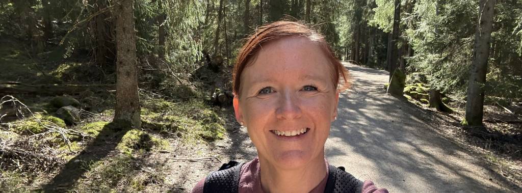 Bilde av student på tur i naturen. Studenten har sekk på ryggen og solen skinner