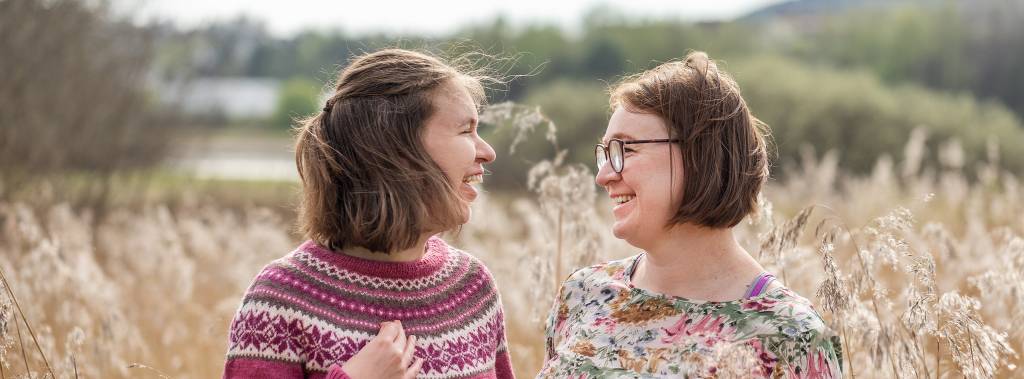 Mor og datter står ute i solen og ser på hverandre imens de smiler